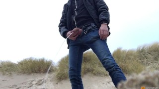young man urinates in the dunes