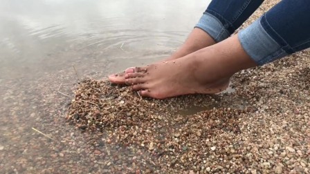 Ebony teen feet at the shore gets covered in sand.