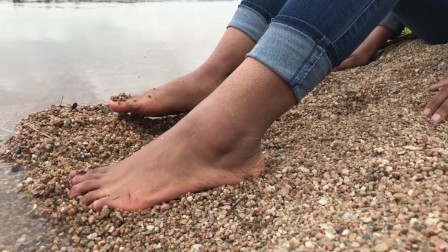 Ebony teen feet at the shore gets covered in sand.