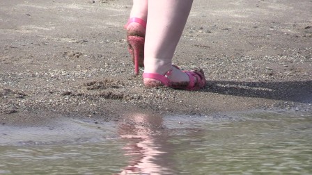 On high heels and bare feet on the sand, plump legs walk along the shore.