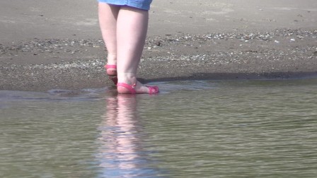 On high heels and bare feet on the sand, plump legs walk along the shore.
