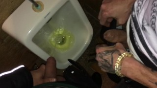 Boys piss and spit together at the urinal after some cocktails