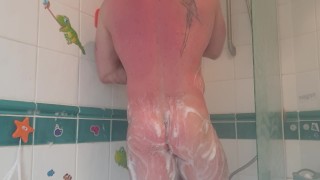 Muscular tattooed guy takes hot shower after the gym
