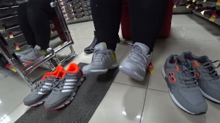 Foot fetish in a public shoe store. Fat legs try on sneakers.