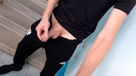 A guy in sweatpants masturbates a big dick in the entrance