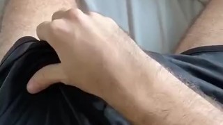 Stroking through shorts before revealing cock