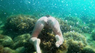 Голая девушка ныряет в океане и показывает свою киску