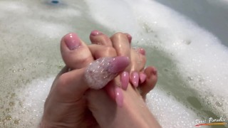 A pretty girl is taking a bath and show her feet in a foam. Wet feet close up. Footfetish