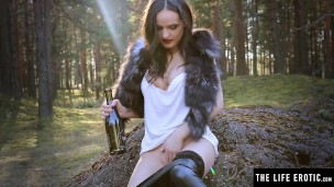 Horny brunette fucks her pussy with a wine bottle in the woods