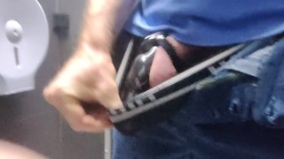 Locked in a chastity cage, man is pissing in a public toilet