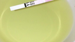Girl pissing on plate over the toilet and doing an ovulation test