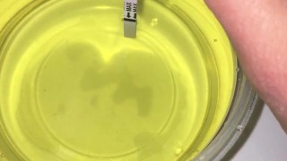 Girl Pissing into a container and plays urine with fingers. 3rd day of ovulation test