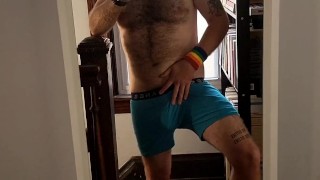 Hairy tattooed guy strips, licks biceps, strokes cock