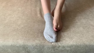 The girl her legs and takes off her socks with her feet