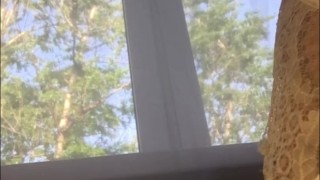 Girl sits on the window and inserts a tampon into her pussy during her period