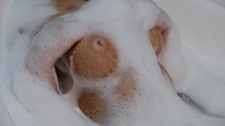 Красивая блондинка принимает ванну и ласкает грудь