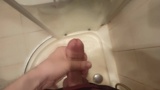 The guy masturbates his dick standing in the shower and cums
