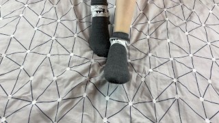 Girl with long legs caresses her feet in gray New Year socks with deer