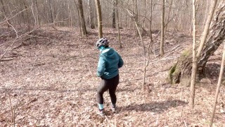 Early spring on bike pissing in the forest near the busy road